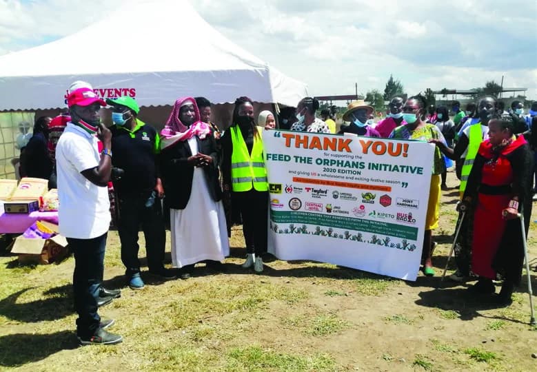 Community partners holding a Feed the Needy banner at an outdoor event